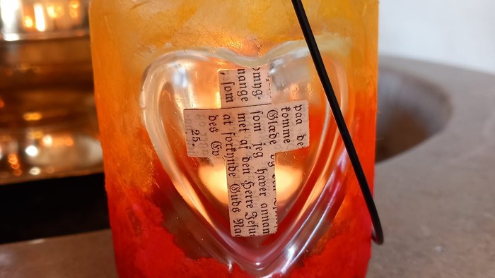 Glas lantern malede orange med et hjerte med papir kors i midten.