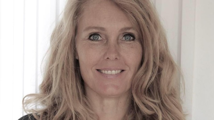 En kvinde med blondt hår og en sort bluse.