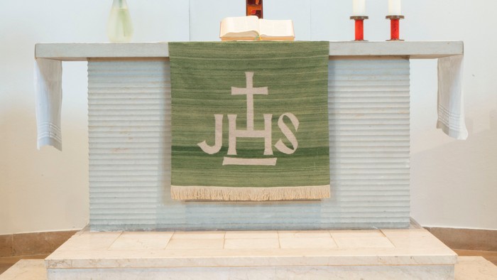 Altar in Kirche mit Kreuz, Kerzen und Blumen