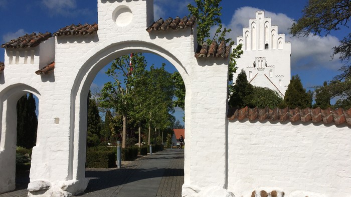 Hvid mur med bueindgang og tårn.