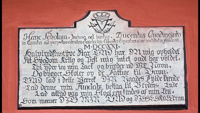 En gravsten med latinsk indskrift og et skjold med heraldiske symboler.