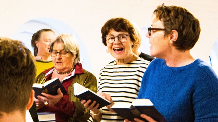 En gruppe af mennesker står sammen og synger i en kirke.