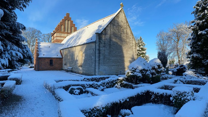 Sneklædt kirke og landskab under klarblå himmel