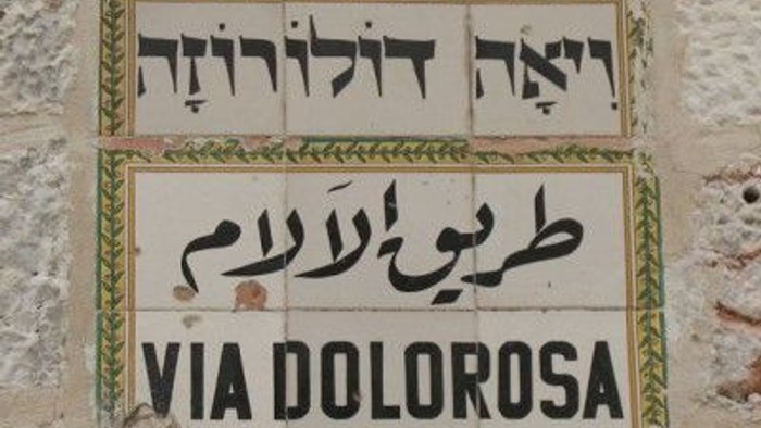 Billedet viser en gadeplade med hebraisk, arabisk og latin skrift, der siger