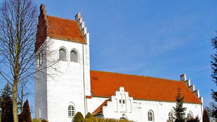 Et hvidt kirkebygning med røde tag og en tårn med bjælker.