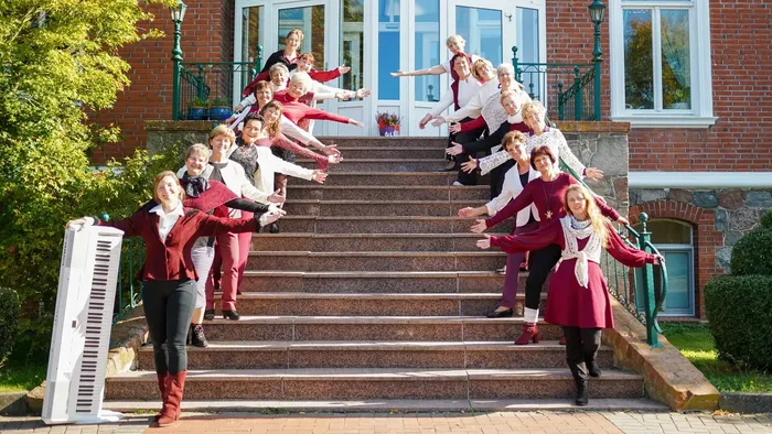 Eine fröhliche Gruppe von Frauen in aufeinander abgestimmten Outfits posiert freudig auf einer großen Backsteintreppe.