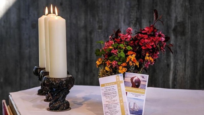 Eleganter Kerzenhalter mit brennenden Kerzen, üppige Blumenarrangements und Informationskarten auf einem Tisch.