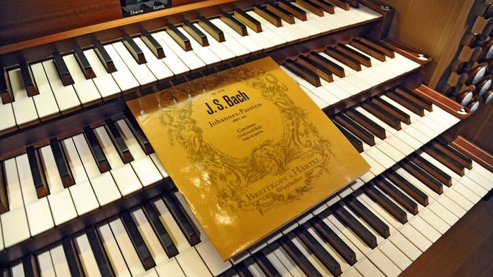 Ein großes Orgelwerk mit einem Notenblattumschlag von J.S. Bachs *„Johannes-Passion“* auf der Klaviatur.