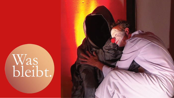 Man sieht einen Pantomime-Clown der den Tod in Form eines Umhanges mit Kapuze umarmt.