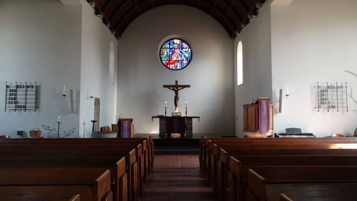 Kirchlicher Innenraum mit Kreuz und Buntglasfenster