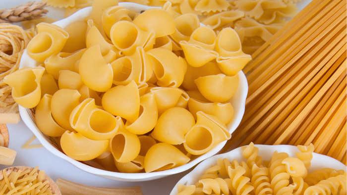 Forskellige typer frisk pasta og semolagryn udstillet på en marmoroverflade.