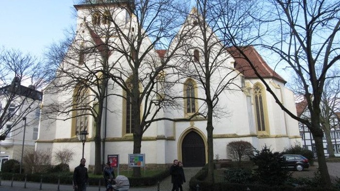 Kirchengemeinde mit Menschen und Autos vor dem Gebäude