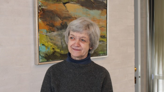 En kvinde står foran et billede af en landskabsmaleri.