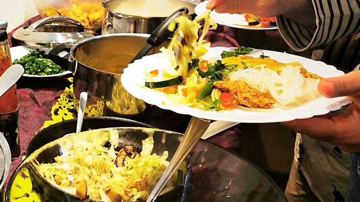 Menschen bedienen sich an einem Buffet mit verschiedenen Gerichten