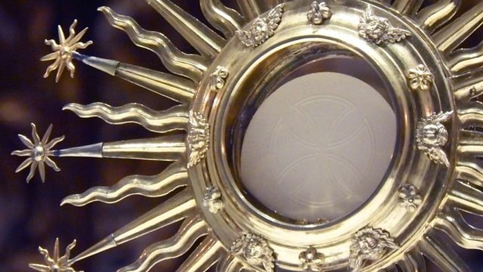 Aufwendig gestaltete goldene Monstranz mit einer runden Hostie, verwendet in der katholischen Eucharistieverehrung.