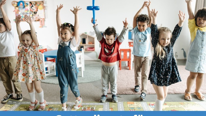 Kinder in einer Gruppe tanzen fröhlich in einem Kindergarten.