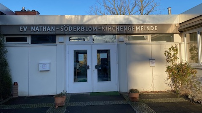 Das Gebäude der EV Nathan-Söderblom-Kirchengemeinde mit Eingangstür und Topfblumen.