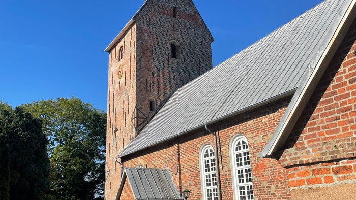 Alte Backsteinkirche mit hohem Turm und blauen Himmel