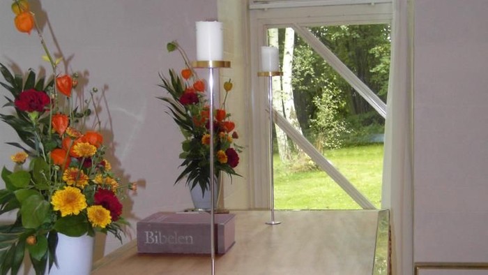 Bord med blomster og lysestage ved vindueskarm