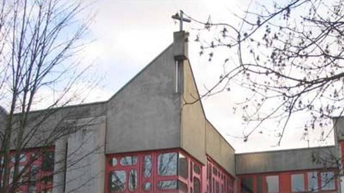 Kirchliches Gebäude mit rotem Zierwerk und Kreuz auf dem Dach