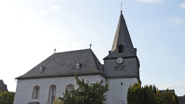 Kleine Kirche mit Uhrturm und grünem Gestrüpp