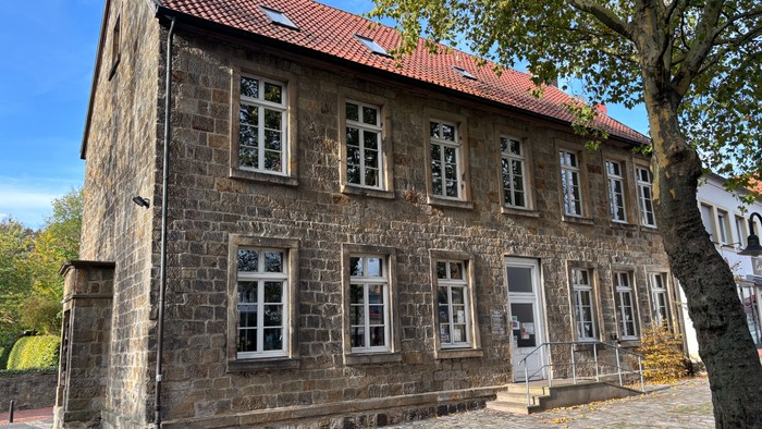 Hier sieht man das Gemeindehaus Alte Schule. Es ist ein zweigeschossiges Sandsteinhaus.