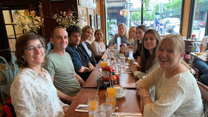 En glad gruppe mennesker, der poserer sammen ved et hyggeligt restaurantbord under et måltid.