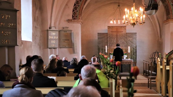En kirke med folk, der sidder på bænkene og en præst ved alteret