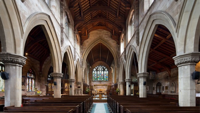 Interior of a large, empty church with wooden pews and arched ceilings.