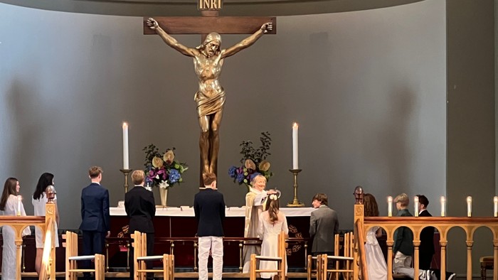Bryllupsceremoni i en kirke med et fremtrædende krucifiks og siddende gæster.