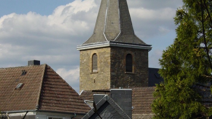 Kirchturm überdacht von Häusern und Bäumen