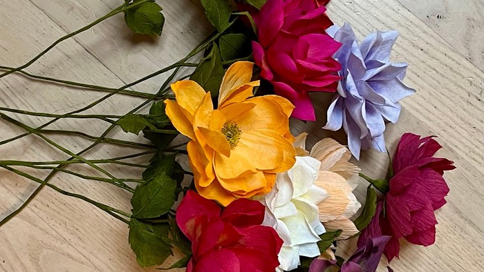 Livligt kunstblomsterbuket i klare gule, røde, lyserøde, lilla og hvide nuancer.