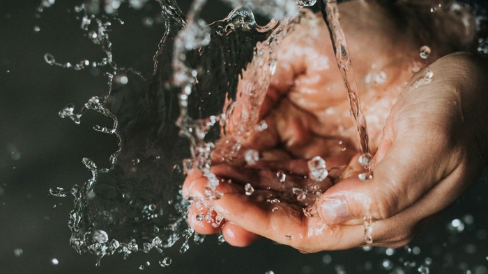 Hände halten Wasser, das herabstürzt