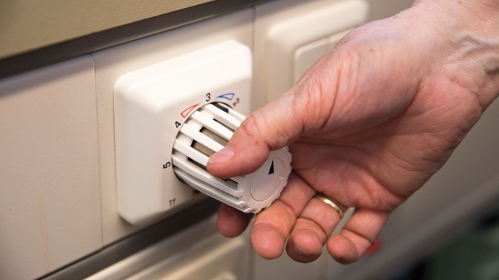 Eine Hand ändert die Temperatur eines Heizkörpers