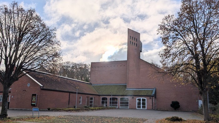 Et rødt teglsteinsbygning med tårn og træer foran