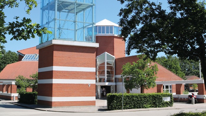 Et moderne glasbygning i en parkagtig omgivelse