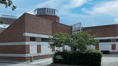 Et moderne bygning med røde mursten og hvide detaljer, med en kuppel og træer foran