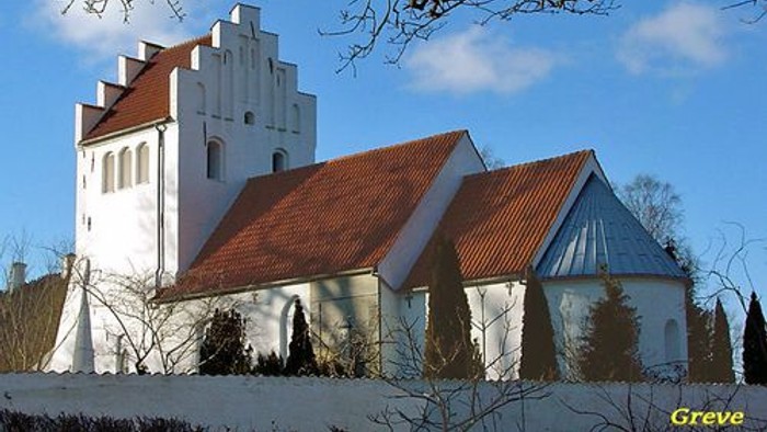 Et hvidt kirkebygning med røde tag og en klokketårn i en snedækked landskab