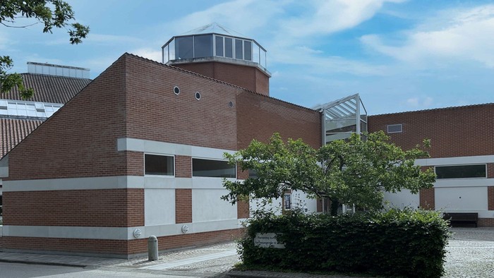 Et moderne bygning med røde mursten og hvide detaljer, med en kuppel og træer foran