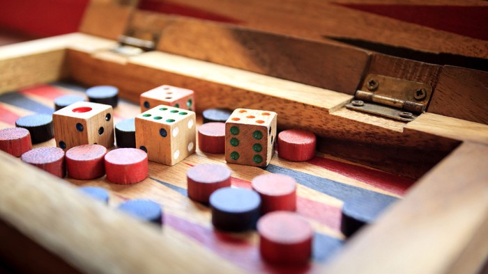 Holzspielzeug, Würfel und Becher auf einem hölzernen Spielbrett