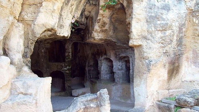 Felsengrab mit aus dem Stein gehauenen Kammern und rauer Felsstruktur, geöffnet und hell vom Tageslicht beleuchtet – Symbol für die Osternacht und die Auferstehung.