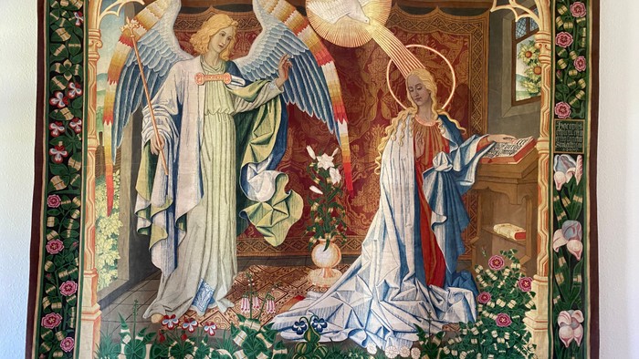 Das Bild zeigt zwei Engel in einem verzierten Rahmen mit Blumen und Text.