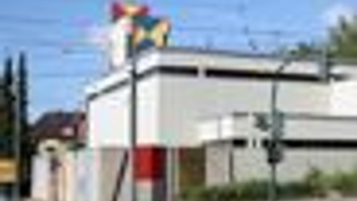 Bunte Tankstelle mit gelben, roten und blauen Akzenten an einer sonnigen Straßenecke.