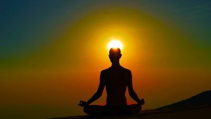 Person meditiert bei Sonnenuntergang