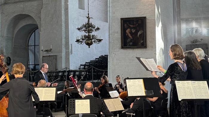 Orchester und Chor, die in einer großen, historischen Kirche mit klassischer Notenmusik auftreten.