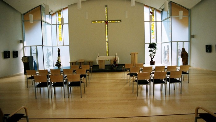 Leere Kirche mit Holzstühlen und großem Kreuz