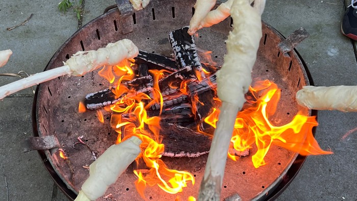 Person kocht Marshmallows über Feuer.