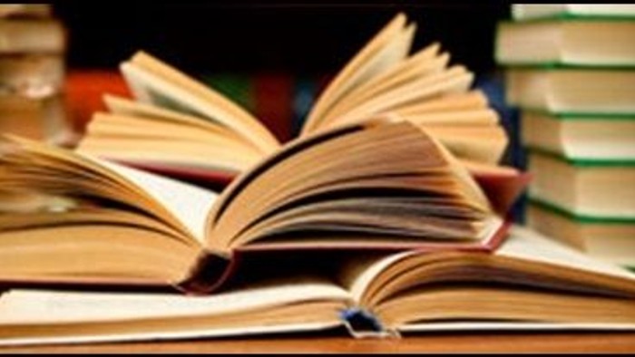 En samling åbne og lukkede bøger på et skrivebord