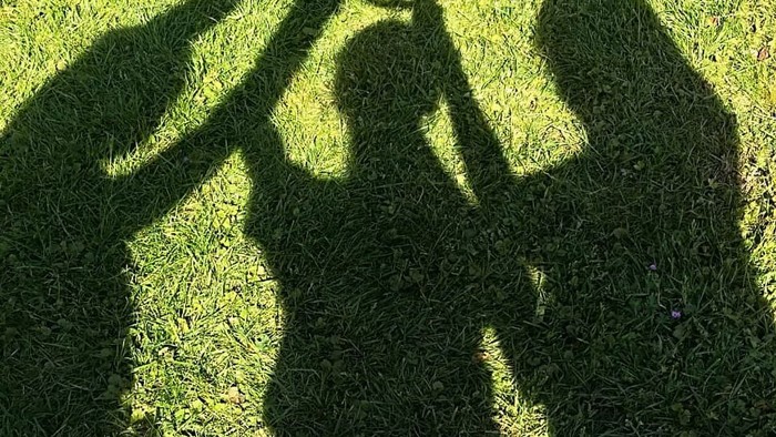 Schatten von zwei Personen auf grünem Gras