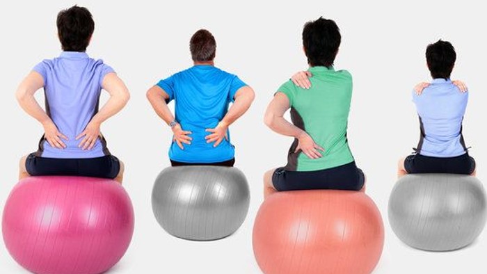 Personen, die auf Gymnastikbällen mit korrekter Haltung sitzen und dabei die Rumpfmuskulatur aktivieren sowie den Rücken stützen.